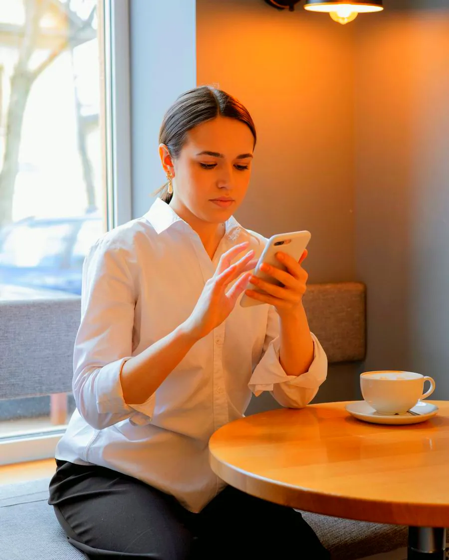 A woman checking her spending on her phone in a café